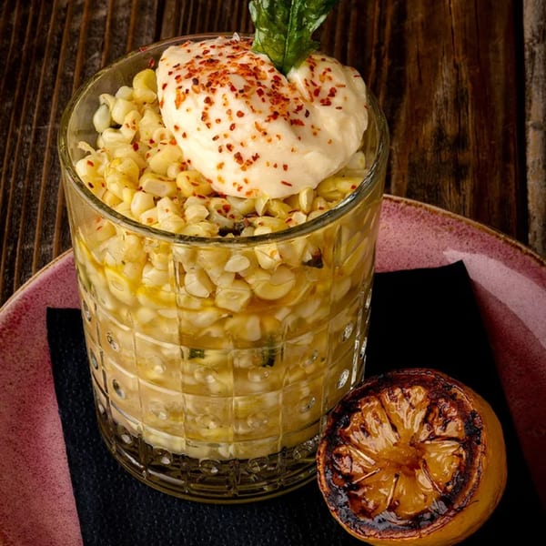 Okay Maguey's Mexican street corn in a glass with crema, chili flakes, and a grilled lime.