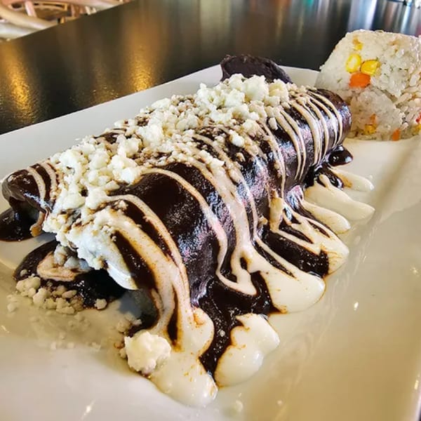 Okay Maguey's enchiladas with dark mole sauce, crema, crumbled cheese, and a side of rice.