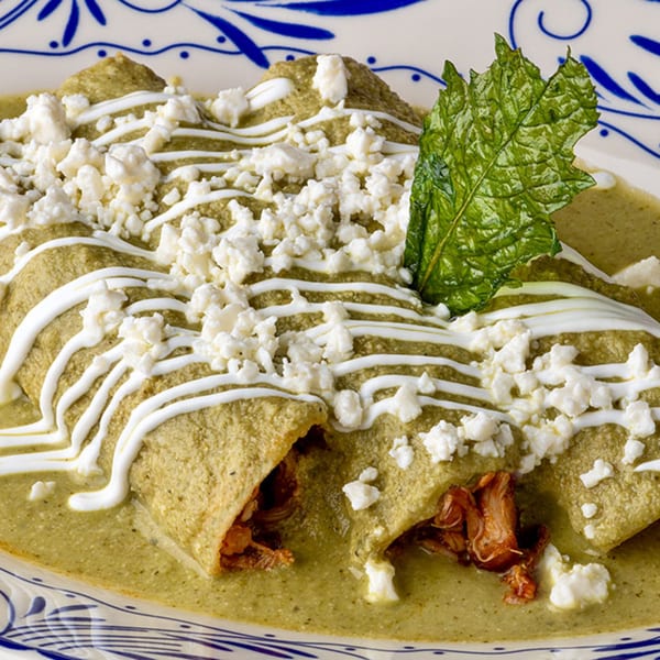 Okay Maguey's enchiladas verdes, topped with crema, crumbled cheese, and a fresh mint leaf.