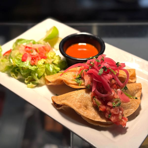 Okay Maguey's Mexican dish with fried tacos, red salsa, pickled onions, and a side salad.